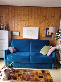 Canapé bleu devant un mur en bois sur lequel sont accrochés des tableaux