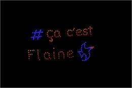 Spectacle de drones lumineux dans un ciel nocturne totalement noir. Les points de lumière forment le