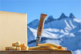 Beaufort et Opinel sur une planche à découper face aux Aiguilles d'Arves en hiver - © OT Saint Sorli