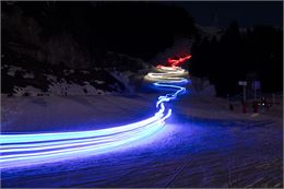 Dans la nuit de Flaine, les moniteurs de l'ESF forment un drapeau français en mouvement. Une traînée