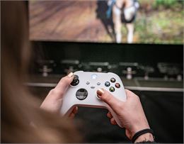 joueuse avec une manette devant un grand écran - Tilby Vattard OTSLA