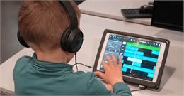 Un enfant écoute sa création musicale sur tablette - La Turbine sciences