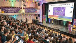 Un large public joue sur tablette ou téléphone au Kahoot! à l'aide d'un animateur sur scène - Gemini
