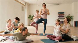 Plusieurs parents pratiquant le yoga avec leurs enfants, chaque adulte accompagnant un enfant - Gemi