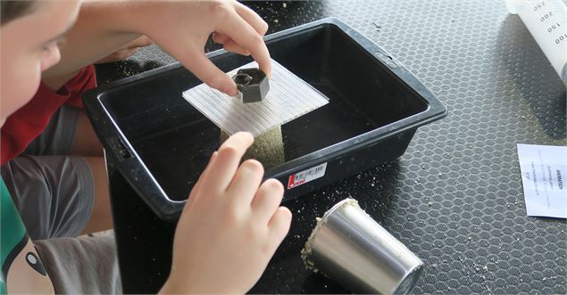 Un enfant expérimente le poids sur du sable - La Turbine sciences