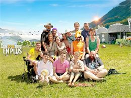 Une affiche de film montrant un groupe de personnes souriantes assises et debout dans un champ d'her