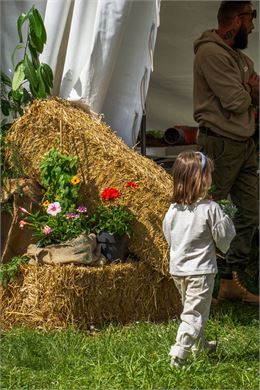 Une petite fille de dos, devant une botte de paille - Marion TODESCHINI