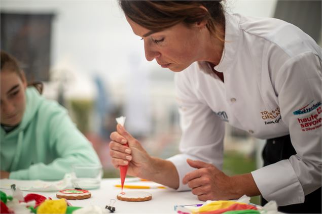Une patissière décore un biscuit à l'aide d'une poche à douille - Image libre de droits