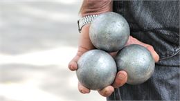 main qui tient trois boules de pétanque - canva