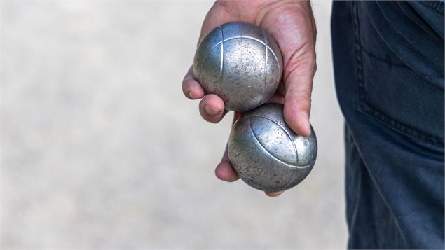 main qui tient deux boules de pétanque - canva
