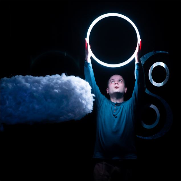 L'artiste tient un cercle lumineux à côté d'un nuage - Compagnie Déo