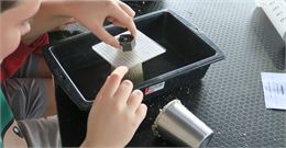 Un enfant expérimente le poids sur du sable - La Turbine sciences