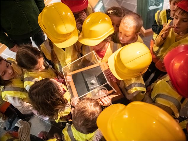 Des enfants avec leur casque de chantier jaune observent une dent - JF. Durand