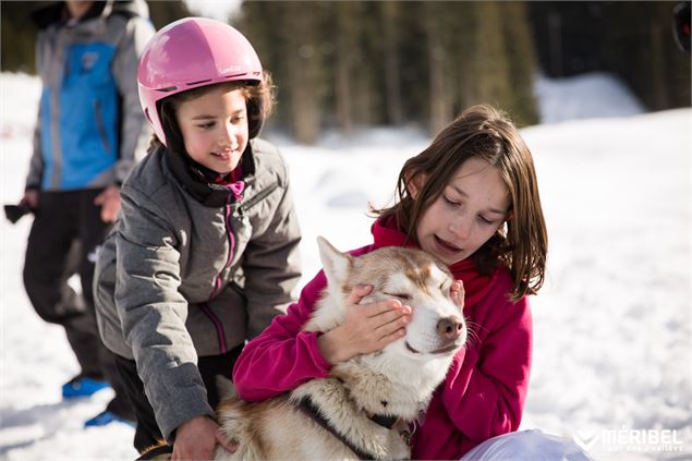 Des enfants caressent les chiens de traineau au village des Inuits - Sylvain Aymoz - Méribel tourism