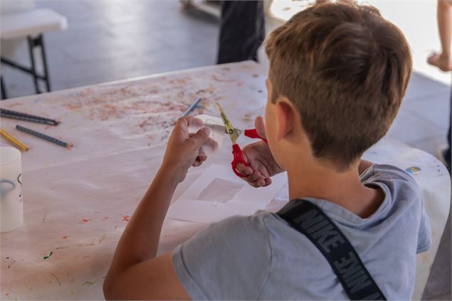Enfant qui découpe son porte clé - @Samoens