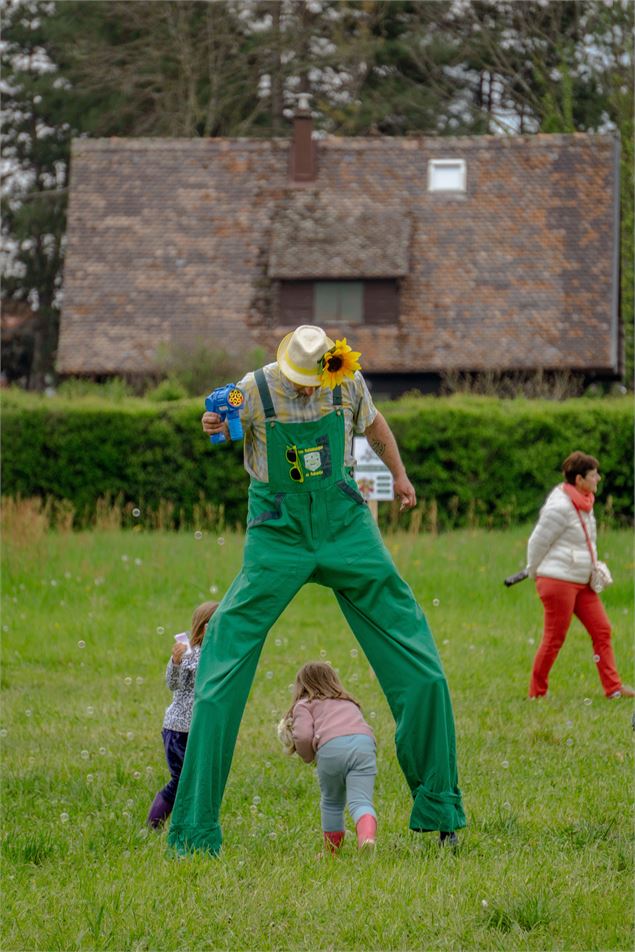 Des enfants jouent avec un homme sur des échasses - Marion TODESCHINI