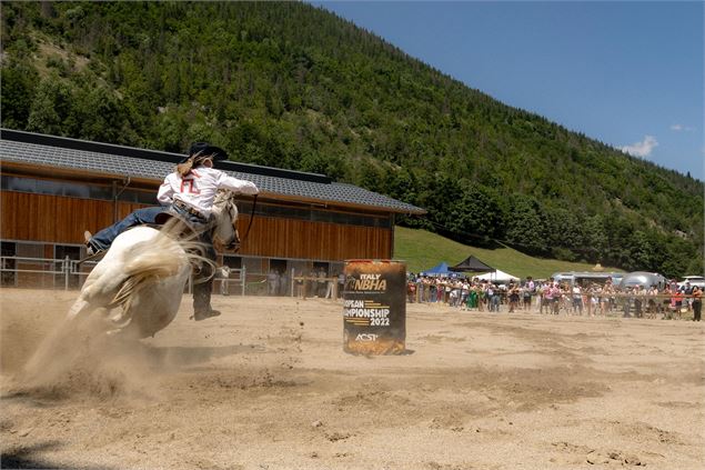 Une cavalière sur son cheval contourne un tonneau à grande allure - Flo Little Ranch