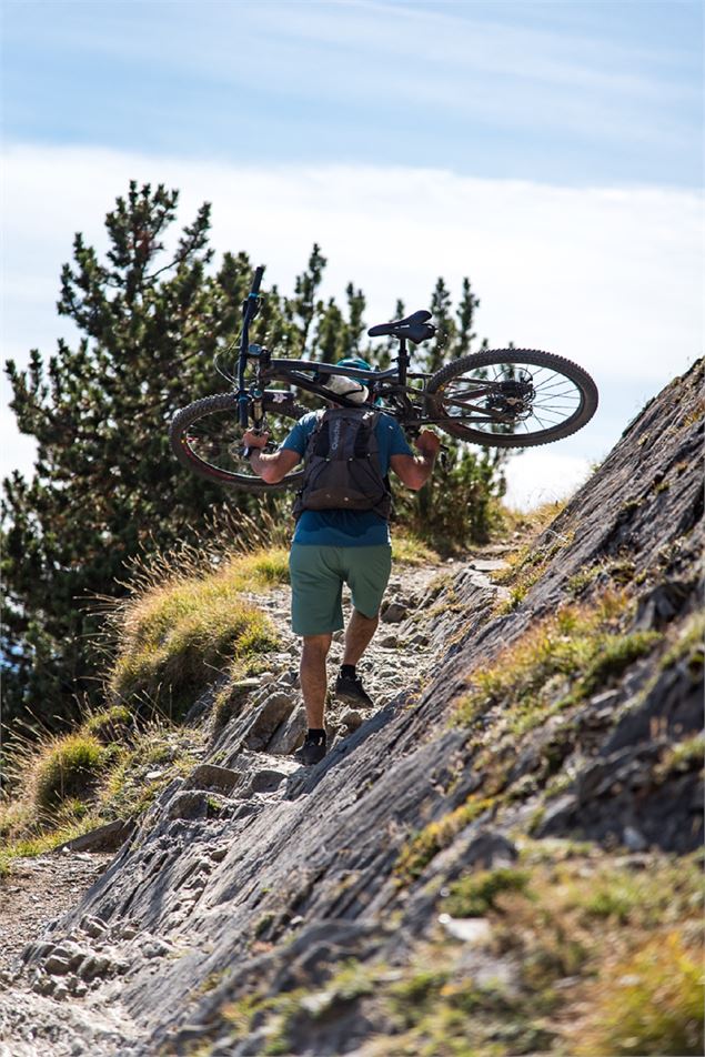 Vttiste  avec son vélo sur le dos pour gravir une cote - A Pernet