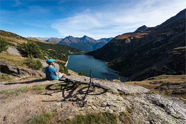 Vttiste admirant la vue sur les barrages depuis un promontoir en pierre - A Pernet