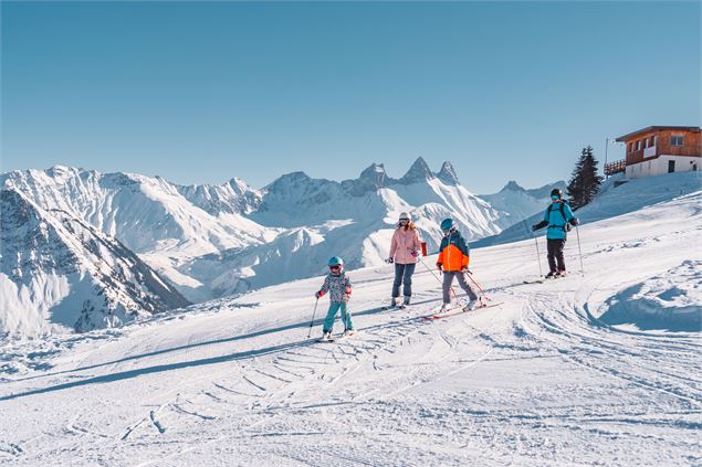 2 enfants et leurs parents qui font du ski après un déjeuner au chalet 2000 - Office de Tourisme Le 