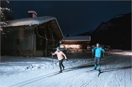 Couple pratiquant le ski nordique en nocturne sur les pistes du domaine du Grand-Bornand - C. Hudry