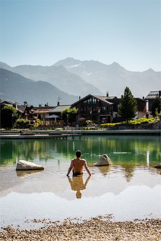 Une personne  est assise dans l'eau au bord du lac - Courchevel Tourisme