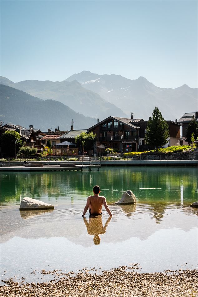 Une personne est assise dans l'eau au bord du lac - Courchevel Tourisme