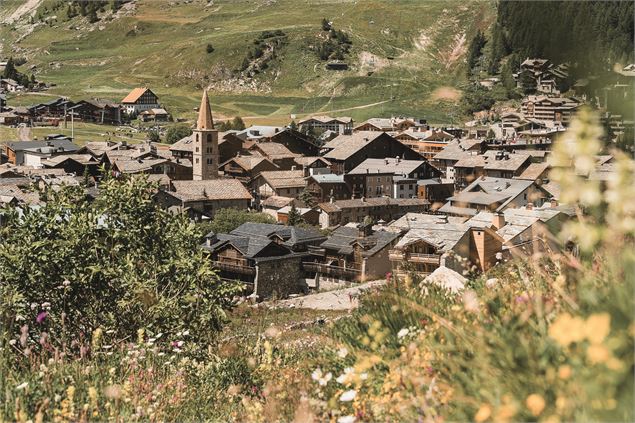 Vue ensoleillée sur le village de Val d'Isère et son clocher depuis le sentier balcon des Barmettes.