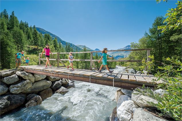 Famille qui marche sur le pont des Cognons ensoleillé - Val d'Isère Tourisme