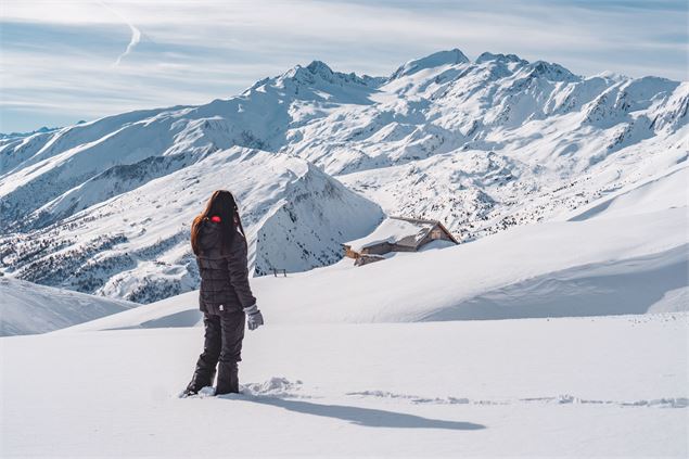 Randonneuse qui admire la vue sur les montagnes enneigées alentours, lors d'une balade sur les crête