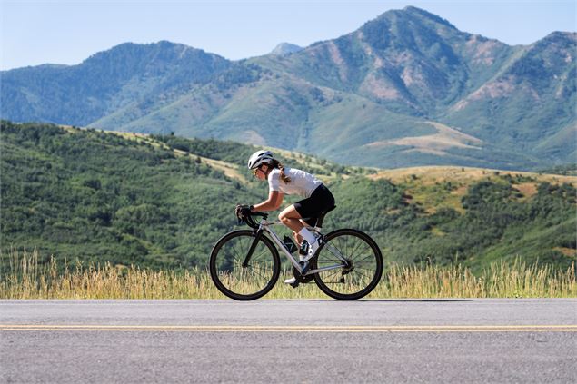 Femme Cycliste qui descend sur une route de montagne - Freepik