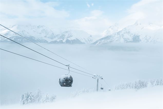 Télécabine de La Norma émergeant de la brume avec les montagnes enneigées en arrière plan. - OTHMV -