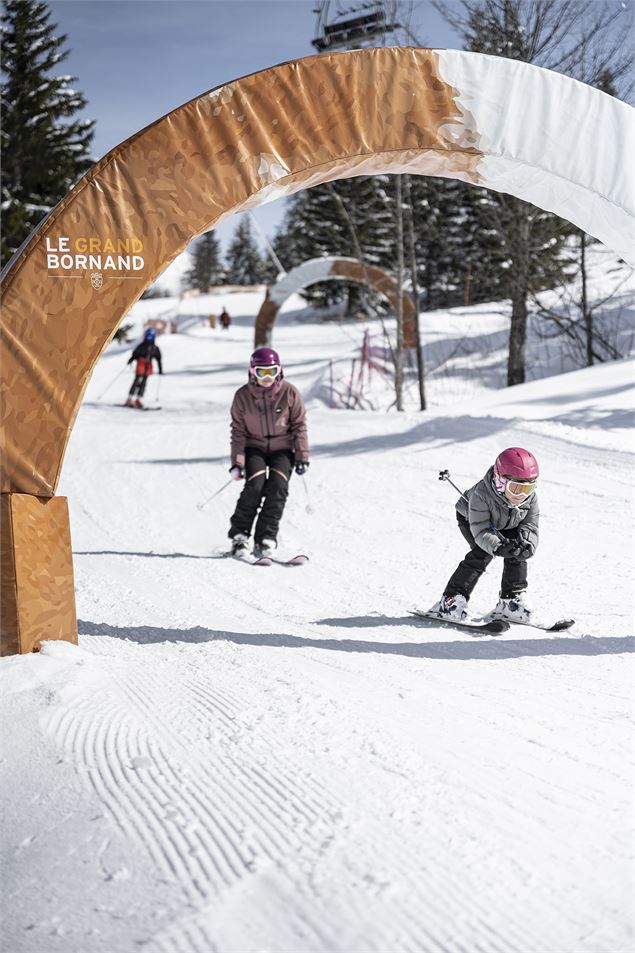 Enfants skiant sur la piste Défi Môm', piste pour les débutants sur le domaine de ski alpin du Grand