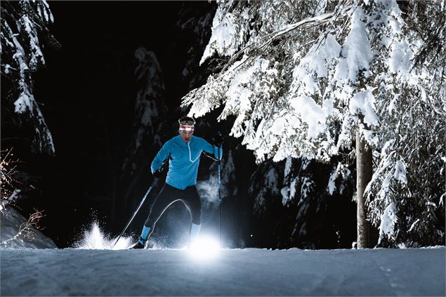 Skieur abordant un virage sur une piste de ski nordique ouverte en nocturne au Grand-Bornand - C. Hu