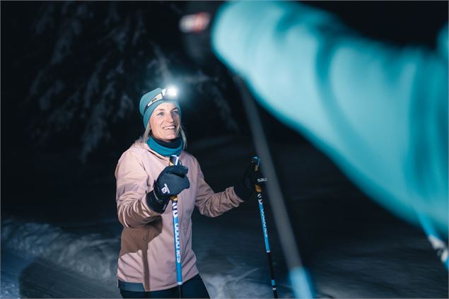 Skieuse portant une lampe frontale sur une piste de ski nordique ouverte en nocturne - C. Hudry