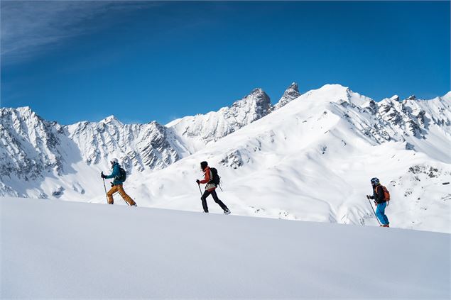 Trois skieurs de randonnée sur la piste des Rhodos à Valloire, vue aiguille d'arves - Thibaut Blais 