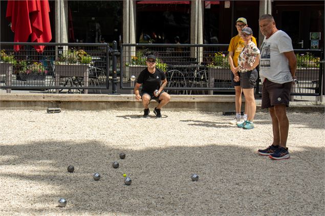 Personne accroupie qui lance une boule de pétanque - OT Flaine - N.Ladrix