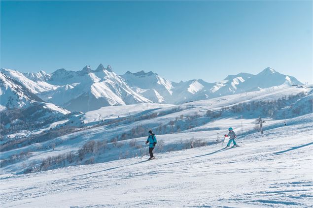 Un papa apprend le ski à sa fille face aux Aiguilles d