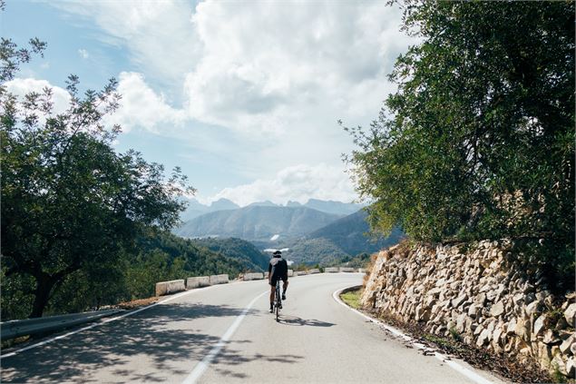 Cycliste qui descend sur une route de montagne - Freepik