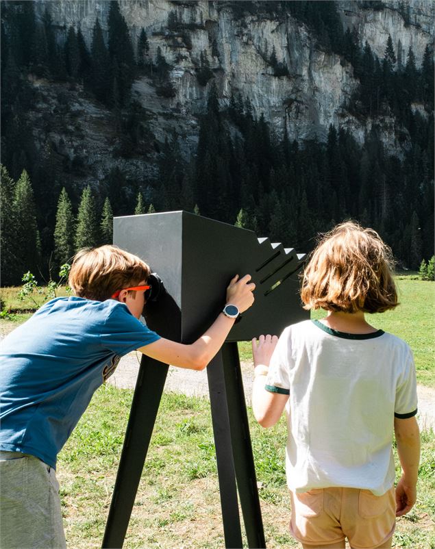 Deux enfants utilisent une longue-vue fixe sur un sentier de montagne. - OT Flaine-Candice Genard