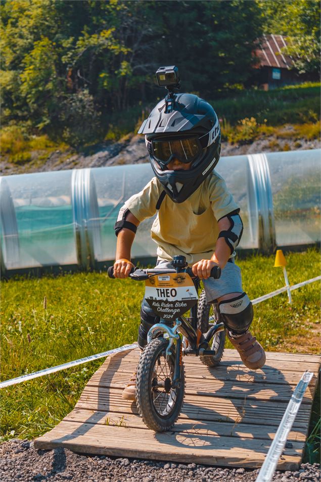 Enfant en draisienne sur un module en bois dans le mini bike park du Corbier - Office de Tourisme Le