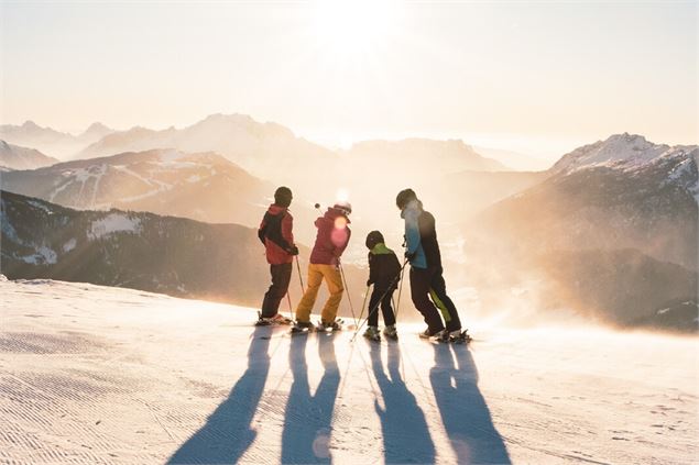 Ski alpin en famille au coucher de soleil sur le domaine skiable du Grand-Bornand - C. Hudry